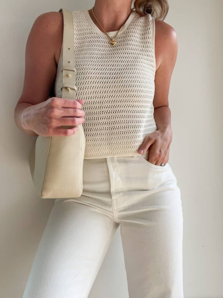 woman wearing an ivory crochet knit tank with off-white jeans and a cream leather Poppy Barley shoulder bag