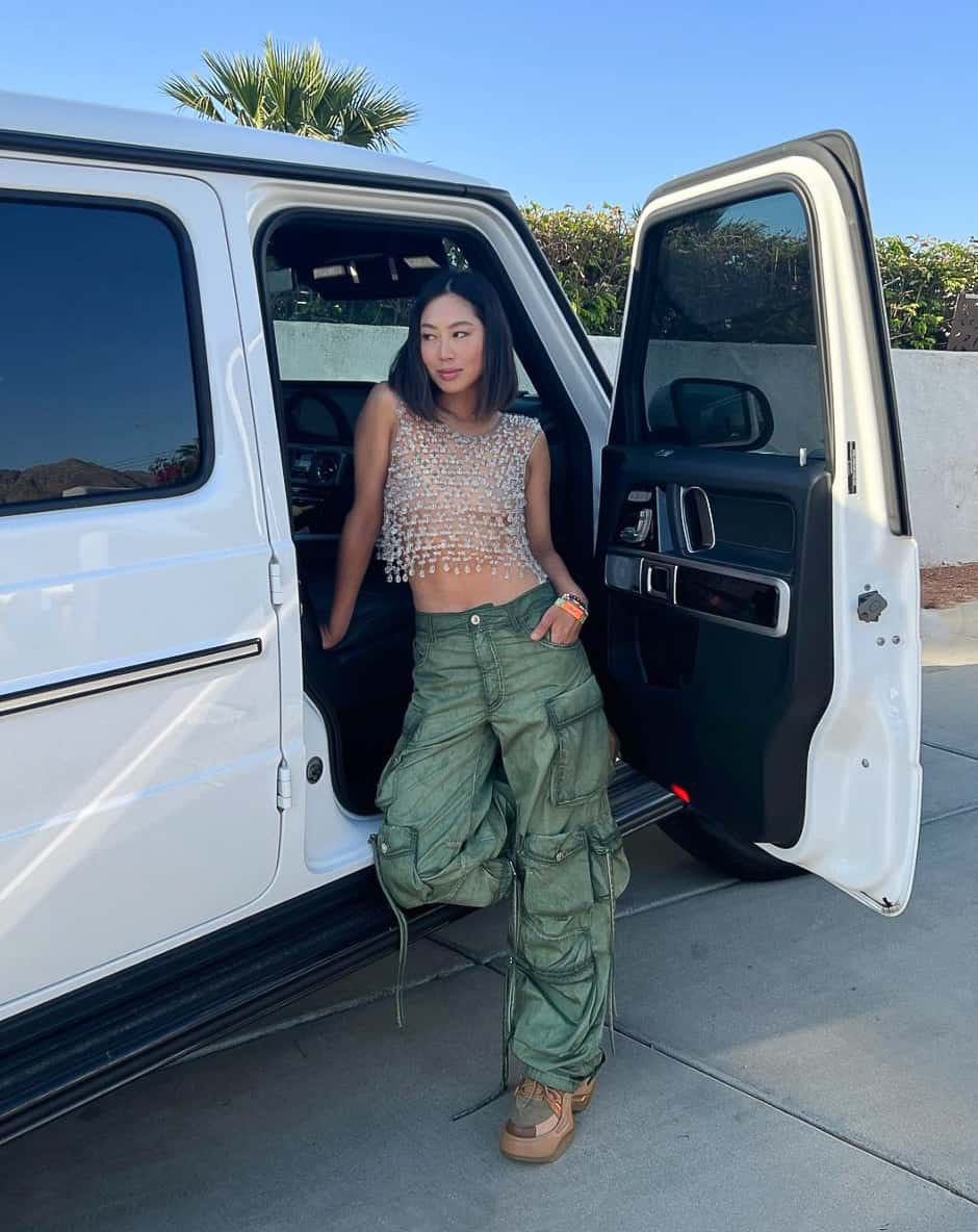 A woman wearing green cargo pants with a cropped crystal embellished tank top and colorful chunky sneakers