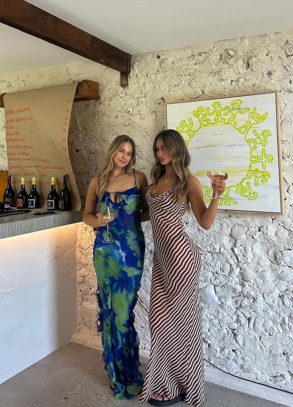 two women at a winery wearing printed maxi slip dresses