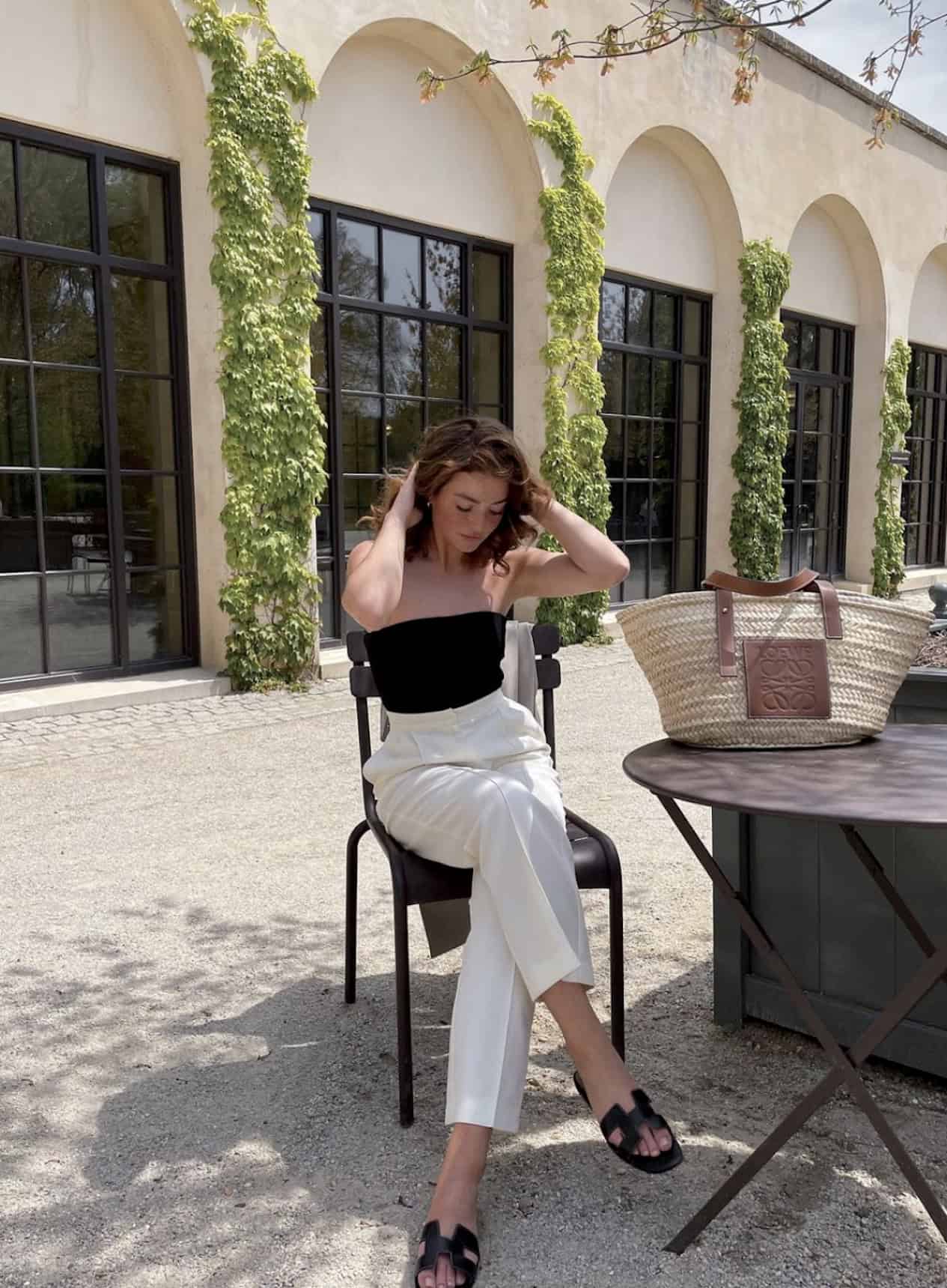 woman wearing a black strapless top with white trousers and black sandals at a winery