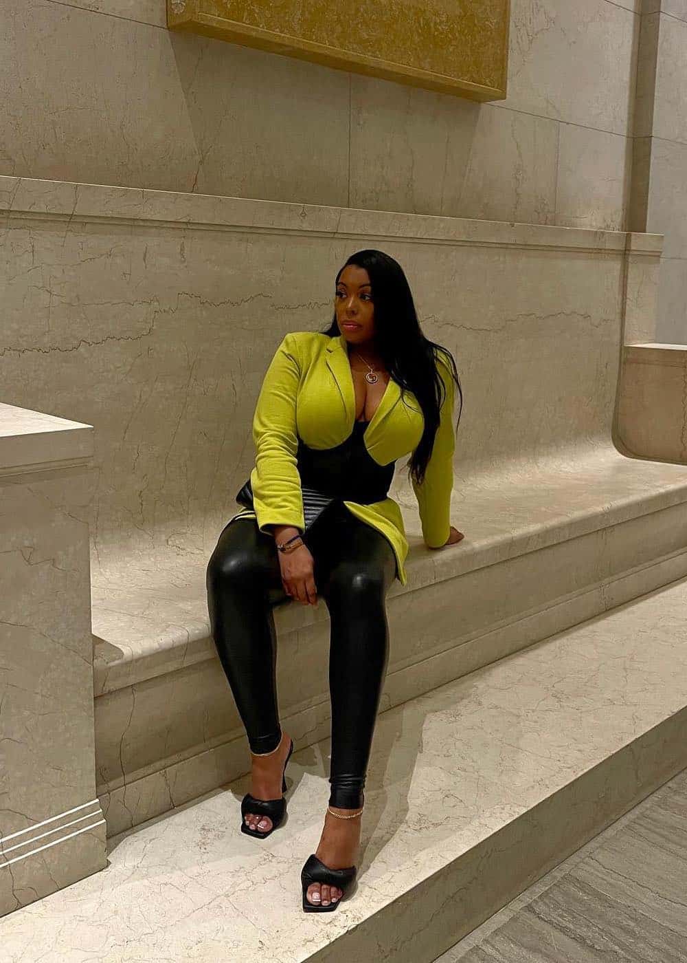 black woman wearing a lime green blazer top with leather leggings and black heels