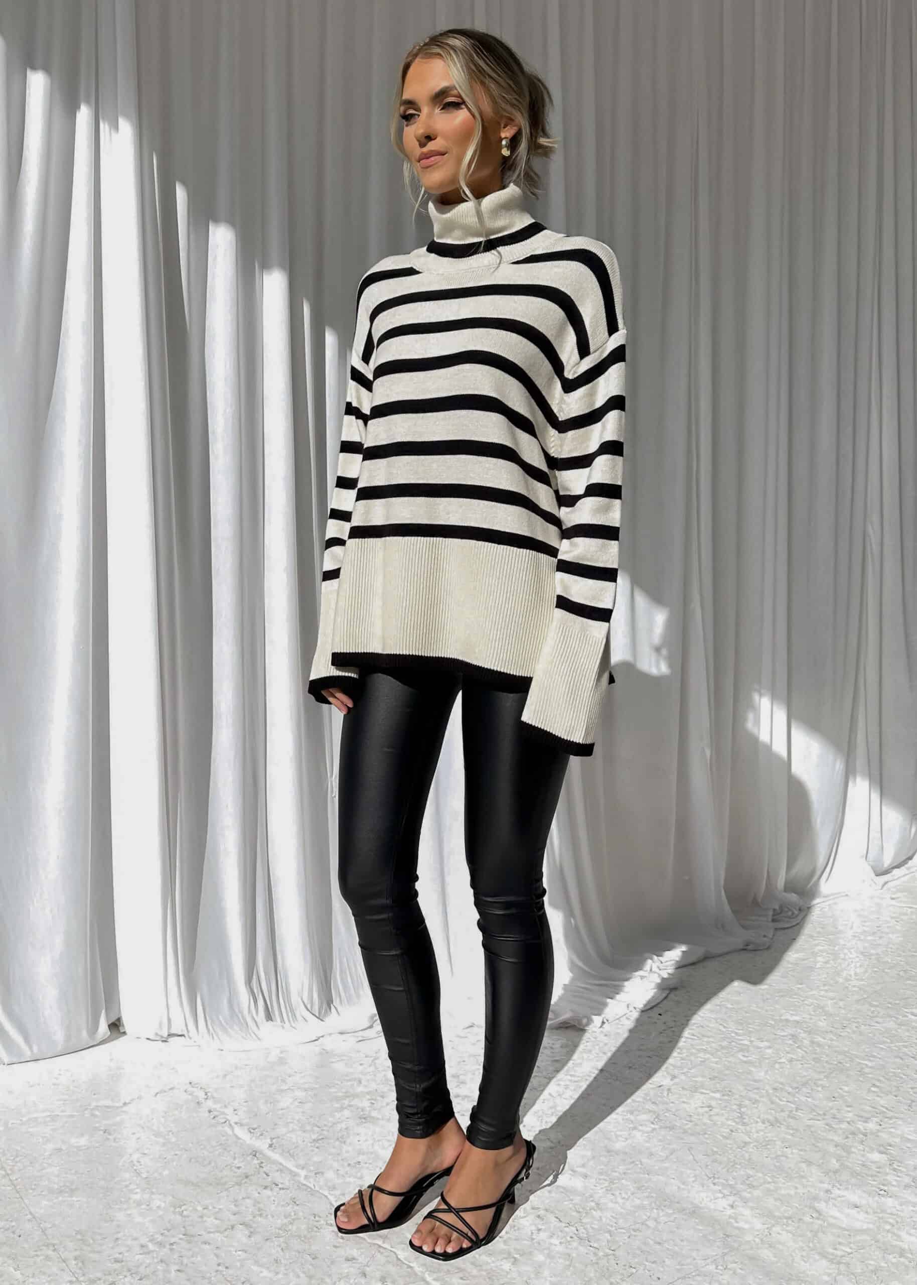 woman wearing an oversized striped sweater with leather leggings and heels