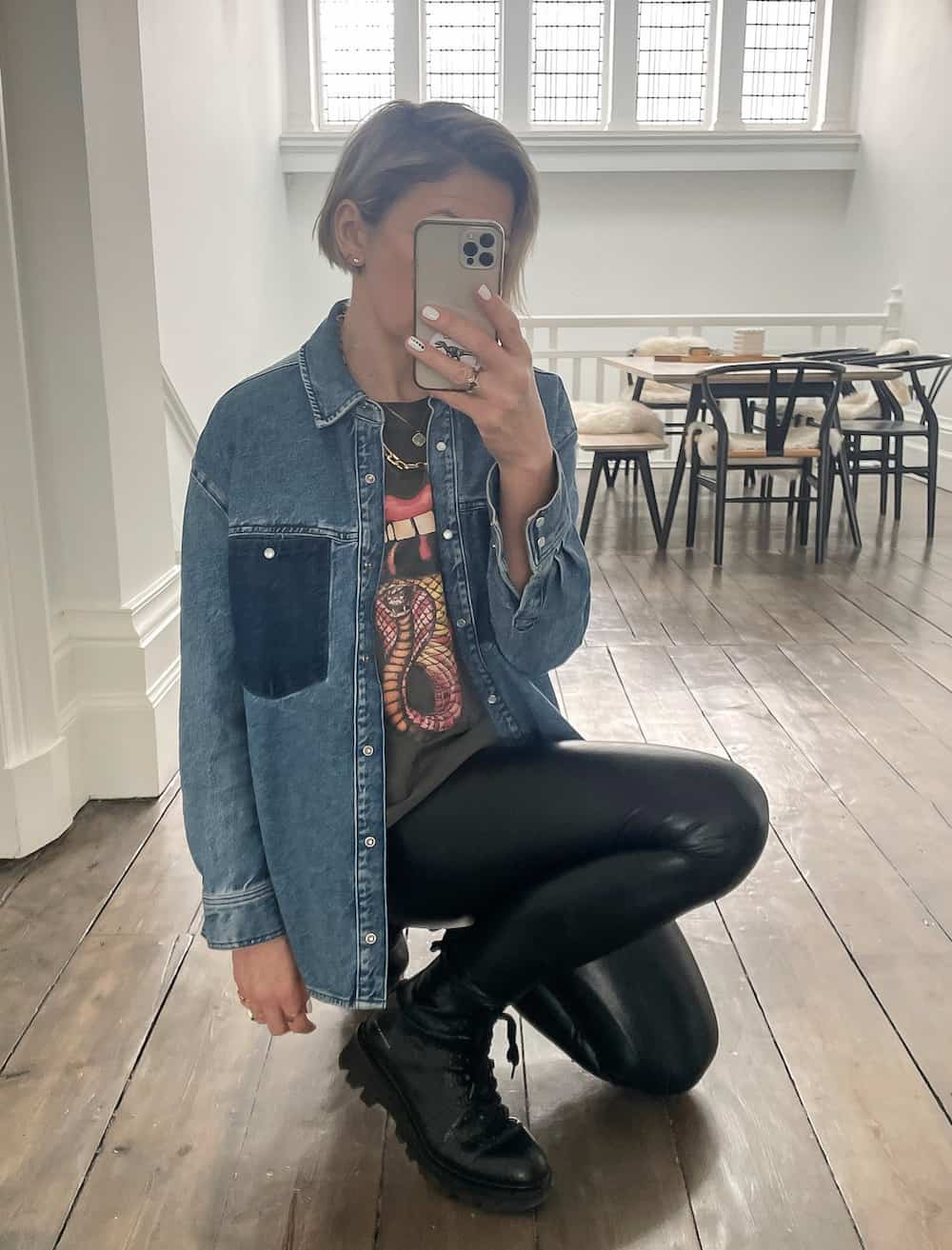 woman wearing a denim shirt over a graphic tee with leather leggings and black combat boots