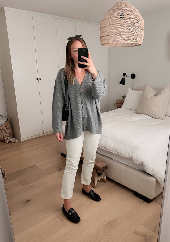 woman wearing a grey knit cardigan with off-white jeans and black loafers