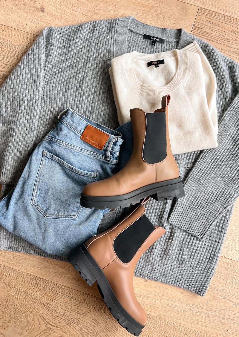 image of a fall capsule wardrobe outfit flat lay with a grey knit cardigan, ivory cashmere t-shirt, blue jeans, and brown lug boots 