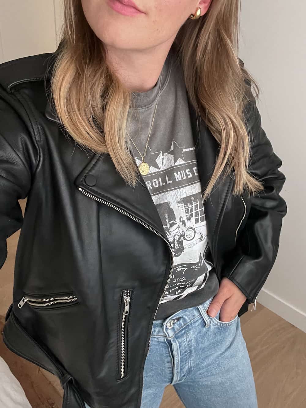 woman wearing a graphic tee with a leather jacket and jeans as part of a capsule wardrobe for fall