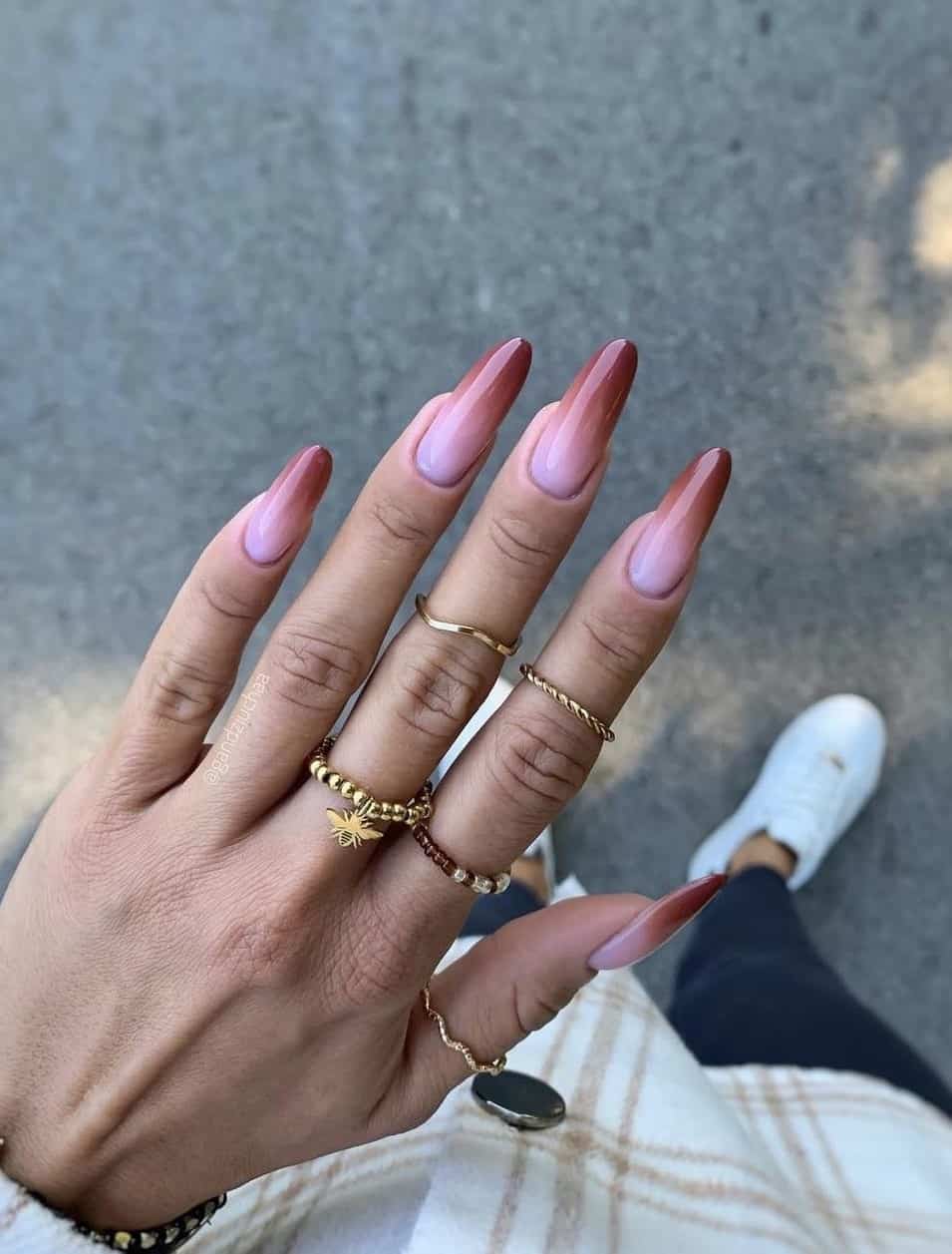 a hand with long round nails painted a nude pink to brown ombre