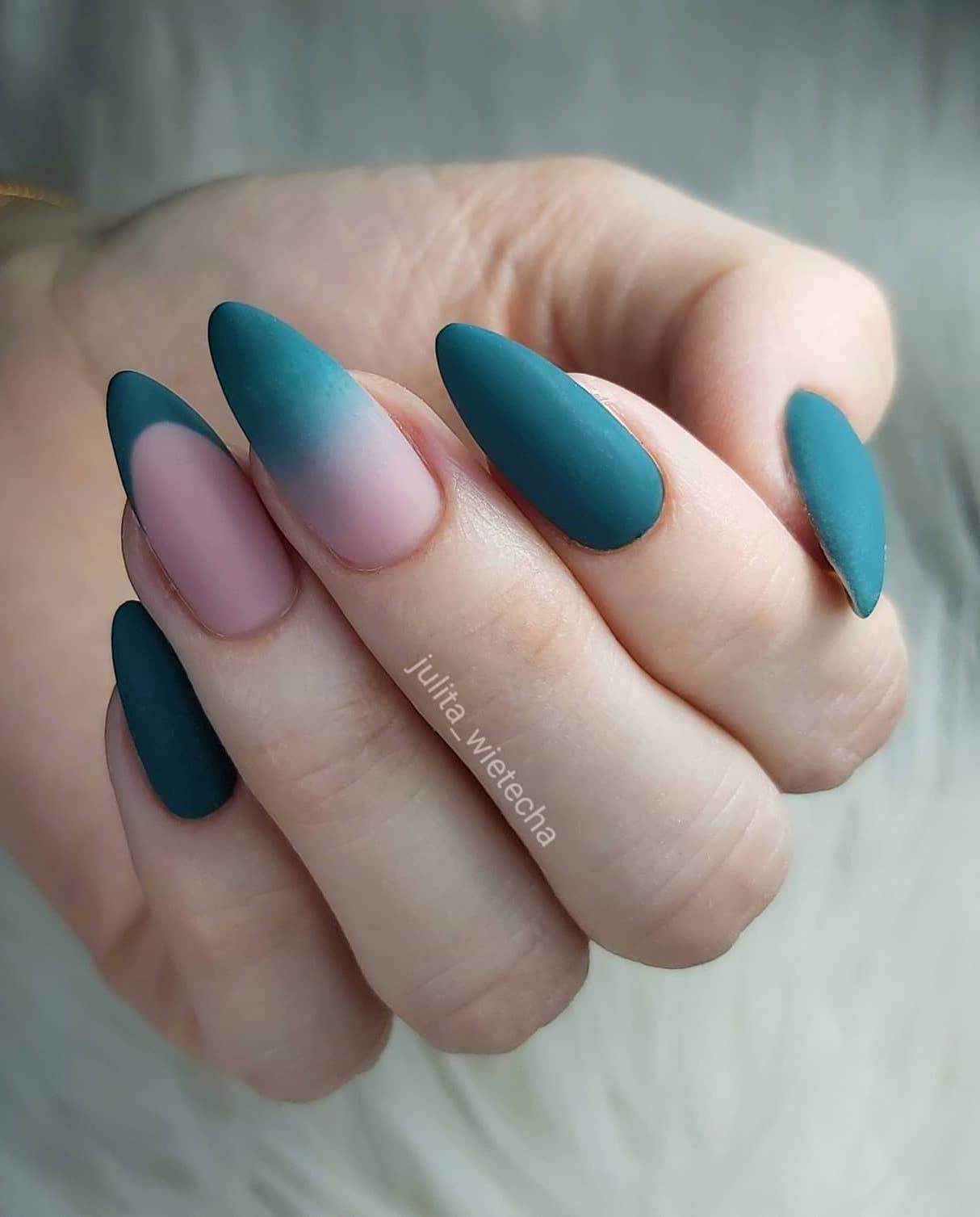 a hand with medium almond nails painted a dark green with a French tip accent nail and a nude to green ombre accent nail