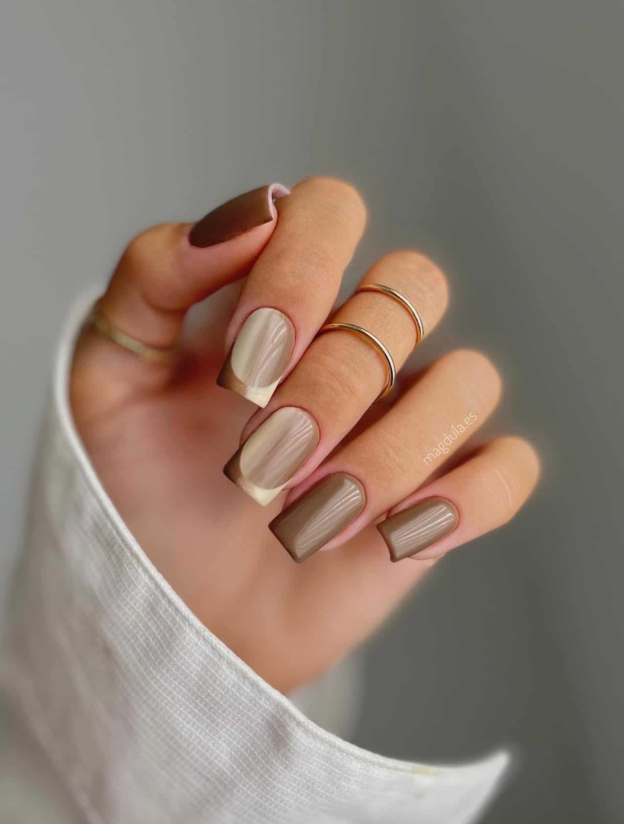 a hand with medium square nails painted brown with beige and brown ombre accent nails with French tips details