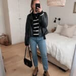 woman wearing a black leather jacket over a black and white striped knit sweater with jeans and brown lug boots for a fall capsule wardrobe outfit