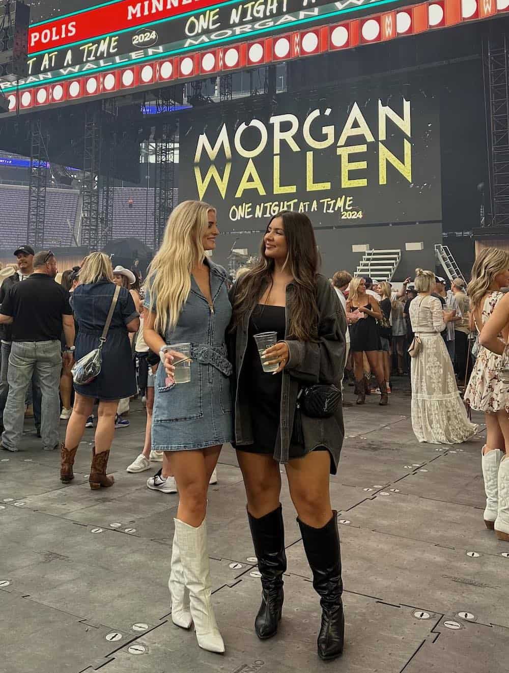 two women standing in front of a Morgan Wallen concert sign wearing cute outfits