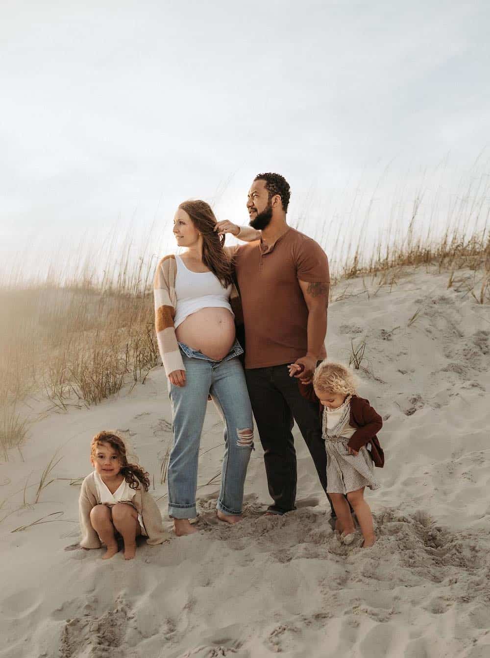 family on a beach for a photoshoot wearing netural colors including brown, white, and beige