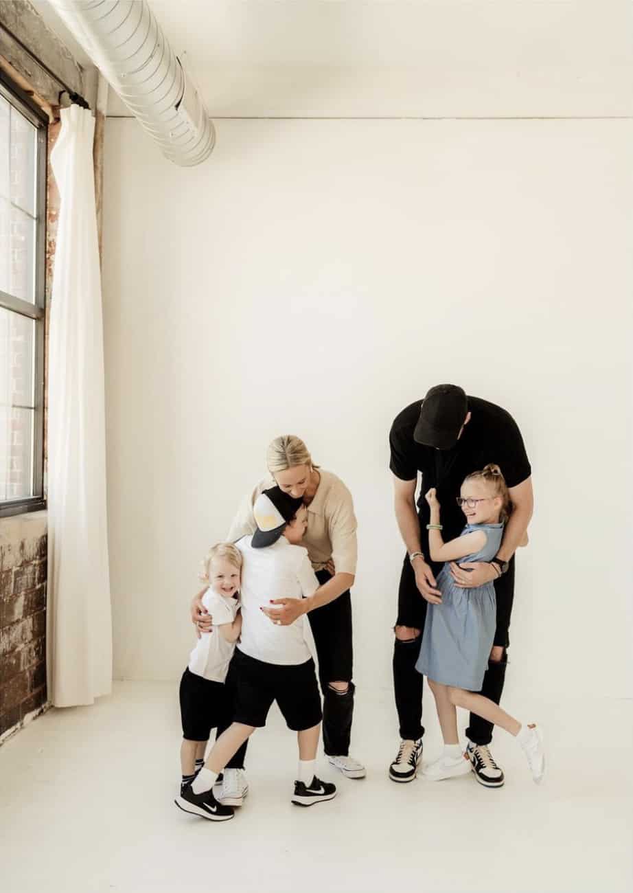 image of a family having a photoshoot wearing neutral colors including white black, beige, and denim
