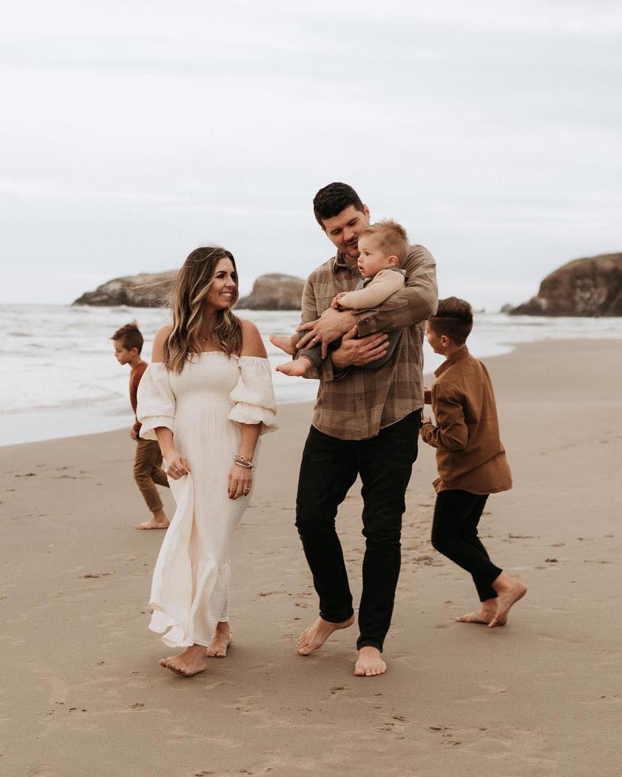 image of a neutral family photoshoot with a woman in a white maxi dress, the dad in a brown top and black jeans, and children in neutral clothing