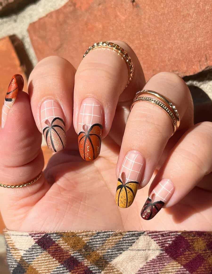 a hand with long round nails painted a matte nude with white grid lines and fall colored pumpkin French tips