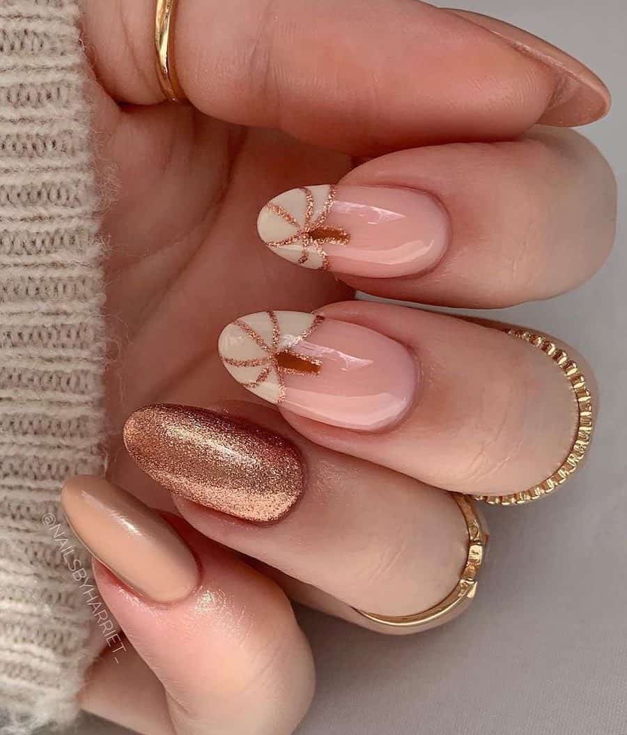 a hand with medium length nails painted a glossy beige, a glitter beige, and glossy nude with cream-colored pumpkins with glitter details