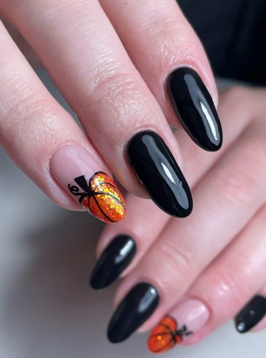 a hand with long glossy black nails with an accent nail featuring a glittery orange pumpkin