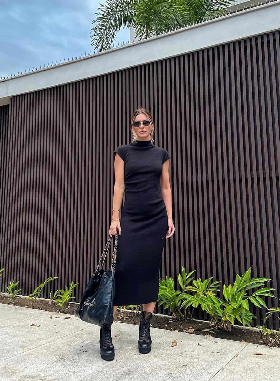 woman wearing a short sleeve midi black sweater dress with black combat boots