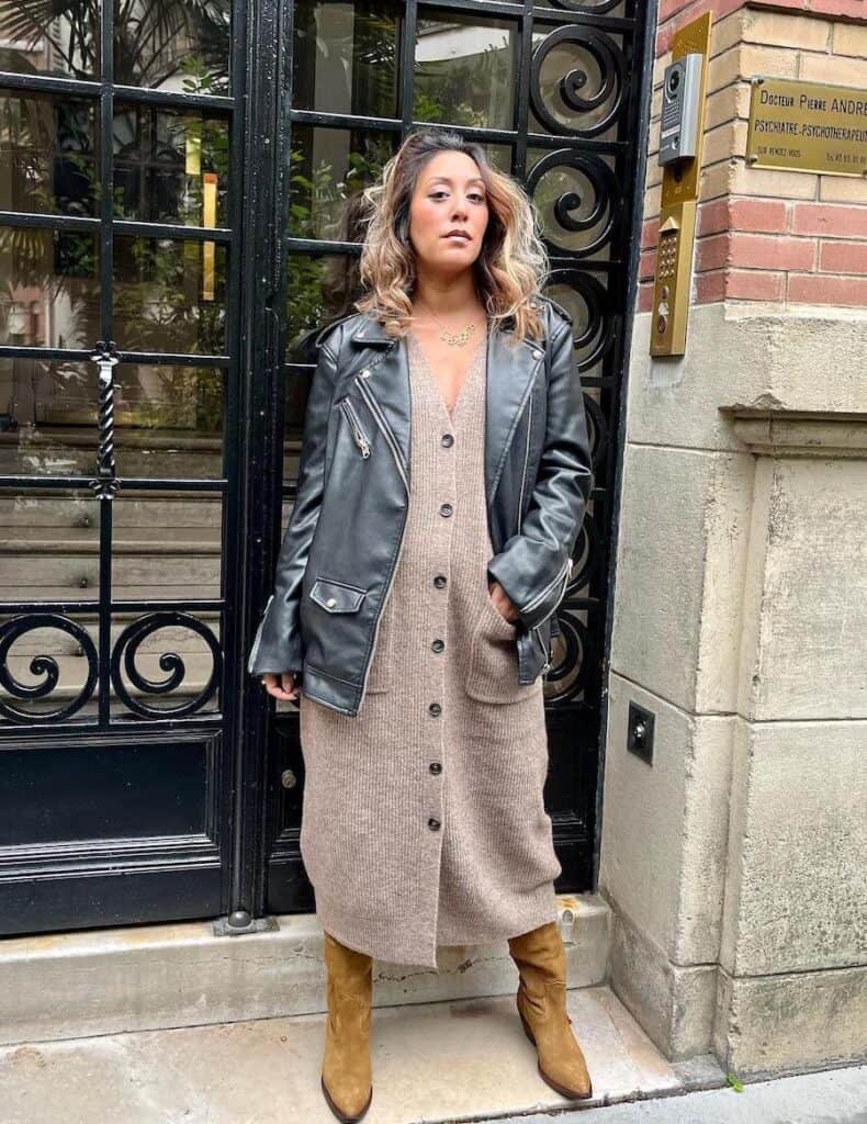 woman wearing a leather jacket over a long sweater dress with suede cowboy boots
