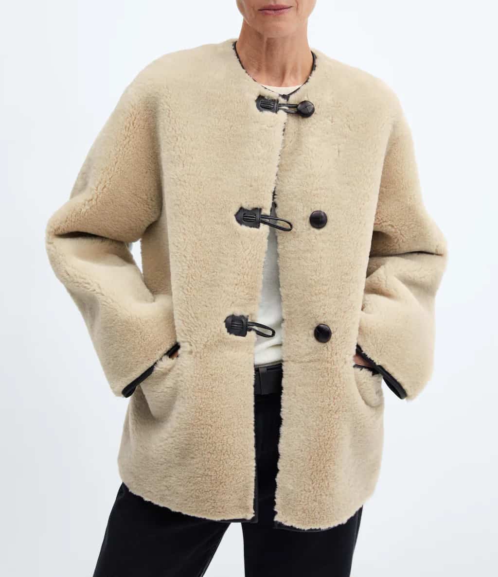 image of an ivory shearling coat with black buttons that is a dupe of the Toteme shearling coat