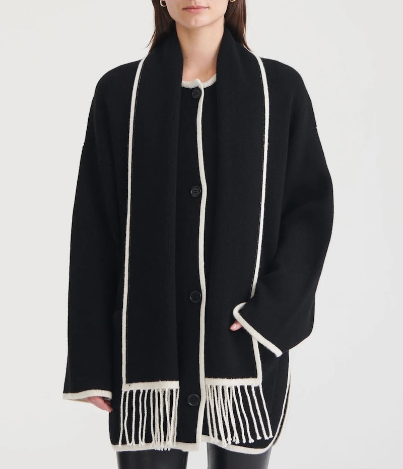 image of a woman wearing a black constrast stitch scarf jacket with white fringe that's a dupe of the Toteme scarf jacket