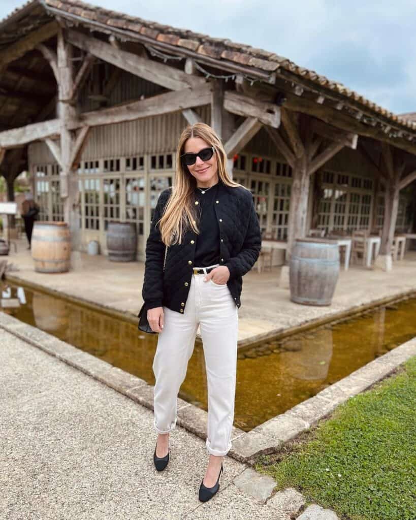 woman wearing a black cropped jacket with a black top and off-white jeans with black low pumps at a winery in the fall