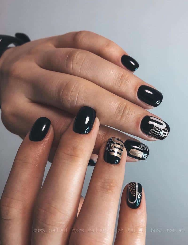 Short glossy black nails with silver and gold geometric details.