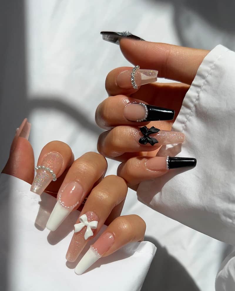 Black and white french tip nails with bow and rhinestone details.