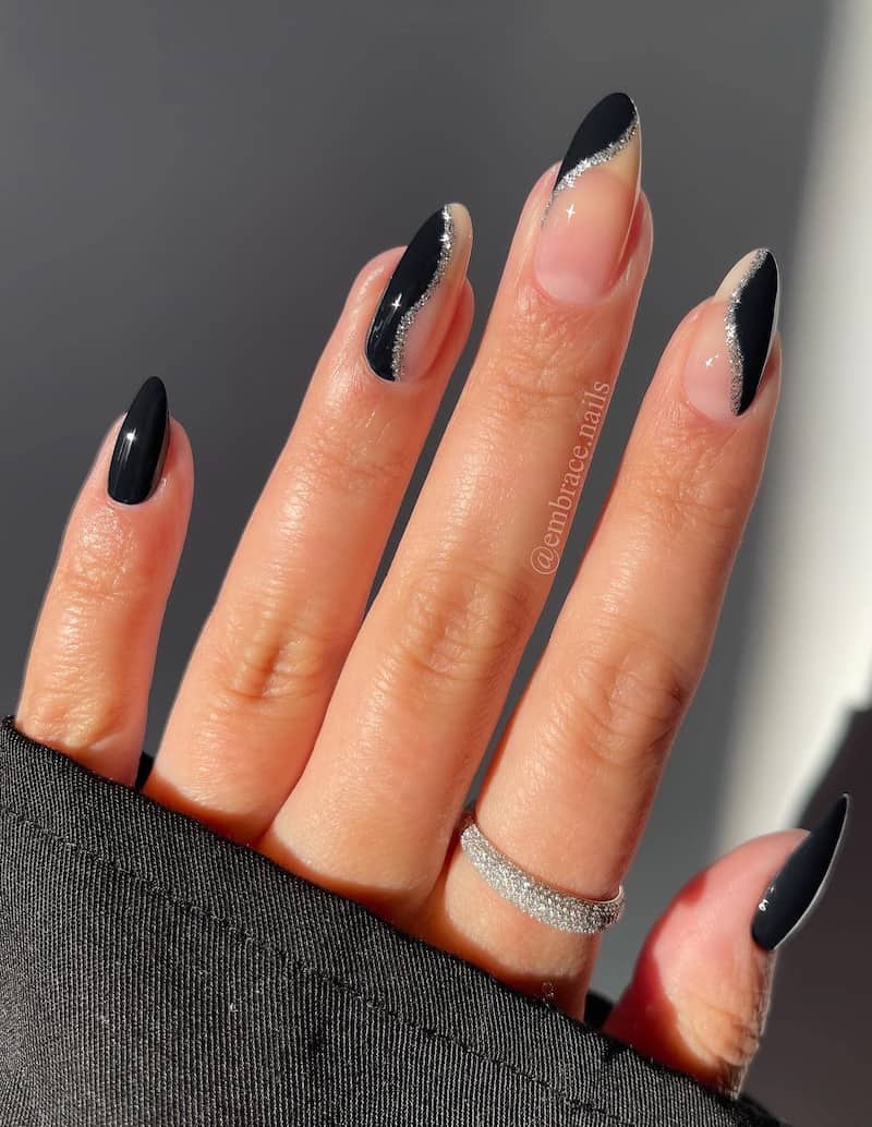 Black french tip nails with silver glitter wave detail.