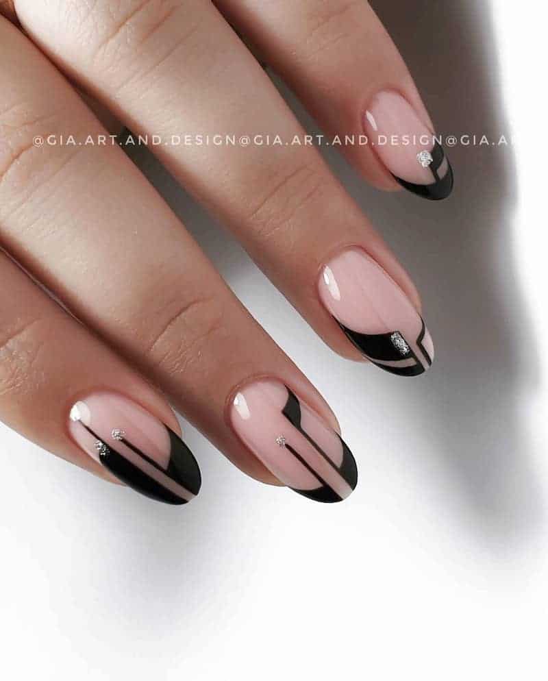 Short nude nails with a black geometric design and silver glitter details.