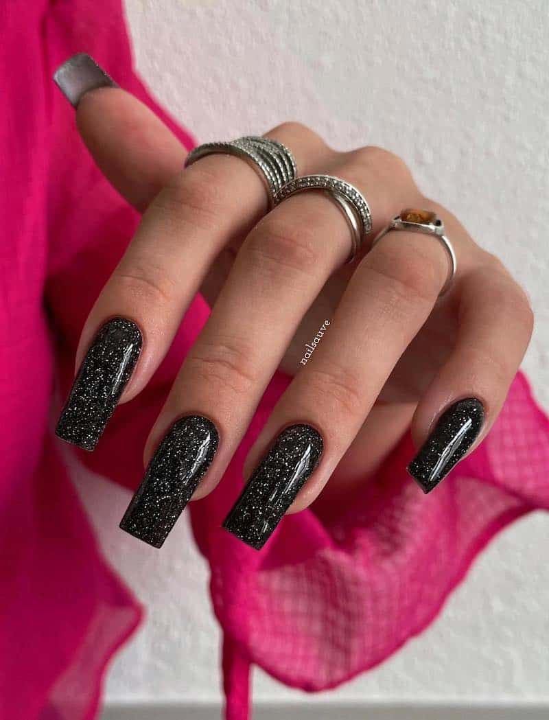 Long, black square nails with silver glitter.