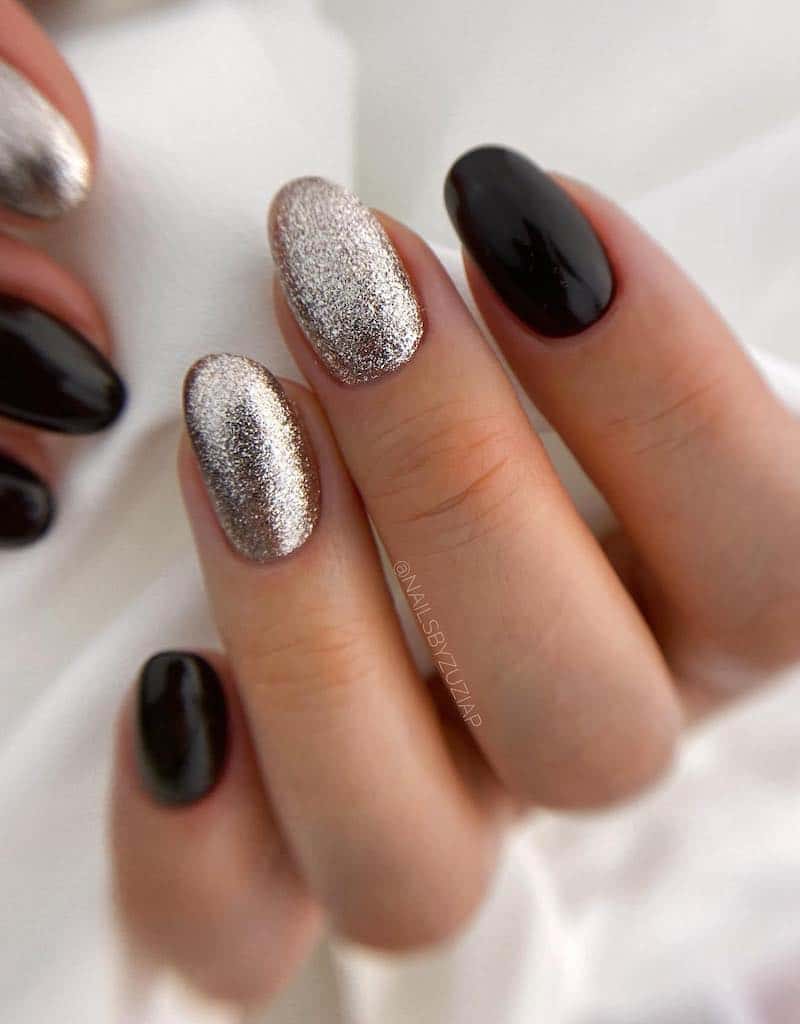 Short glossy black nails and silver foil glitter accent nails.