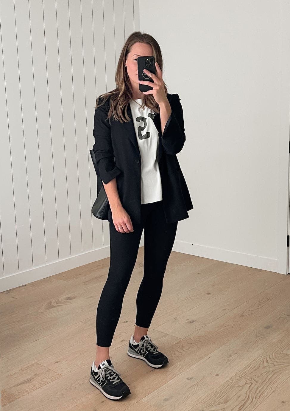 woman wearing a black blazer outfit with a white t-shirt, black leggings, and black sneakers