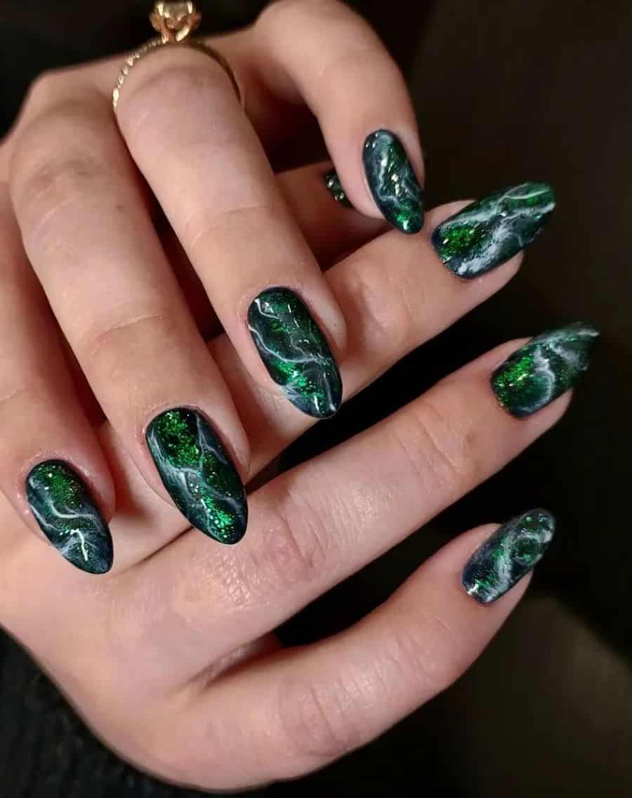 A hand with medium almond nails with marbled emerald green, white, and green glitter polish