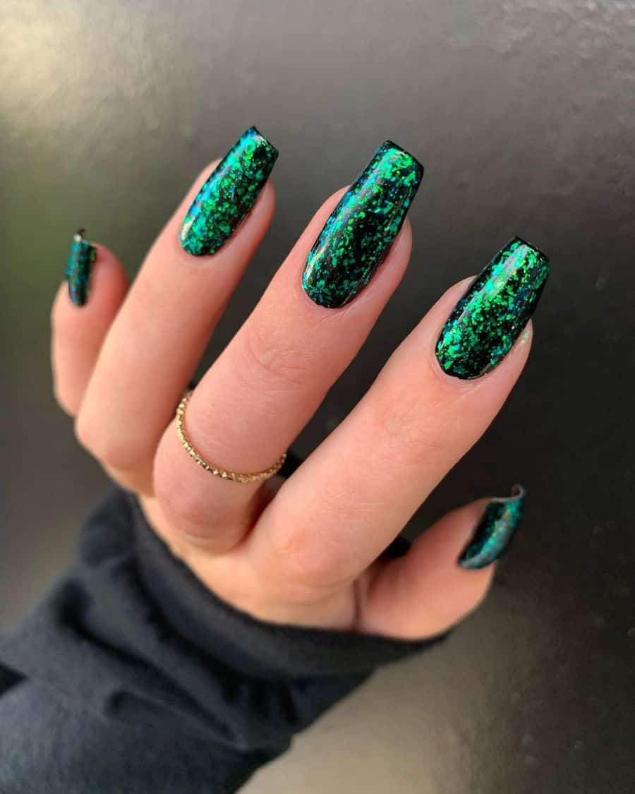 A hand with medium coffin nails with black and emerald green chunky glitter nail polish