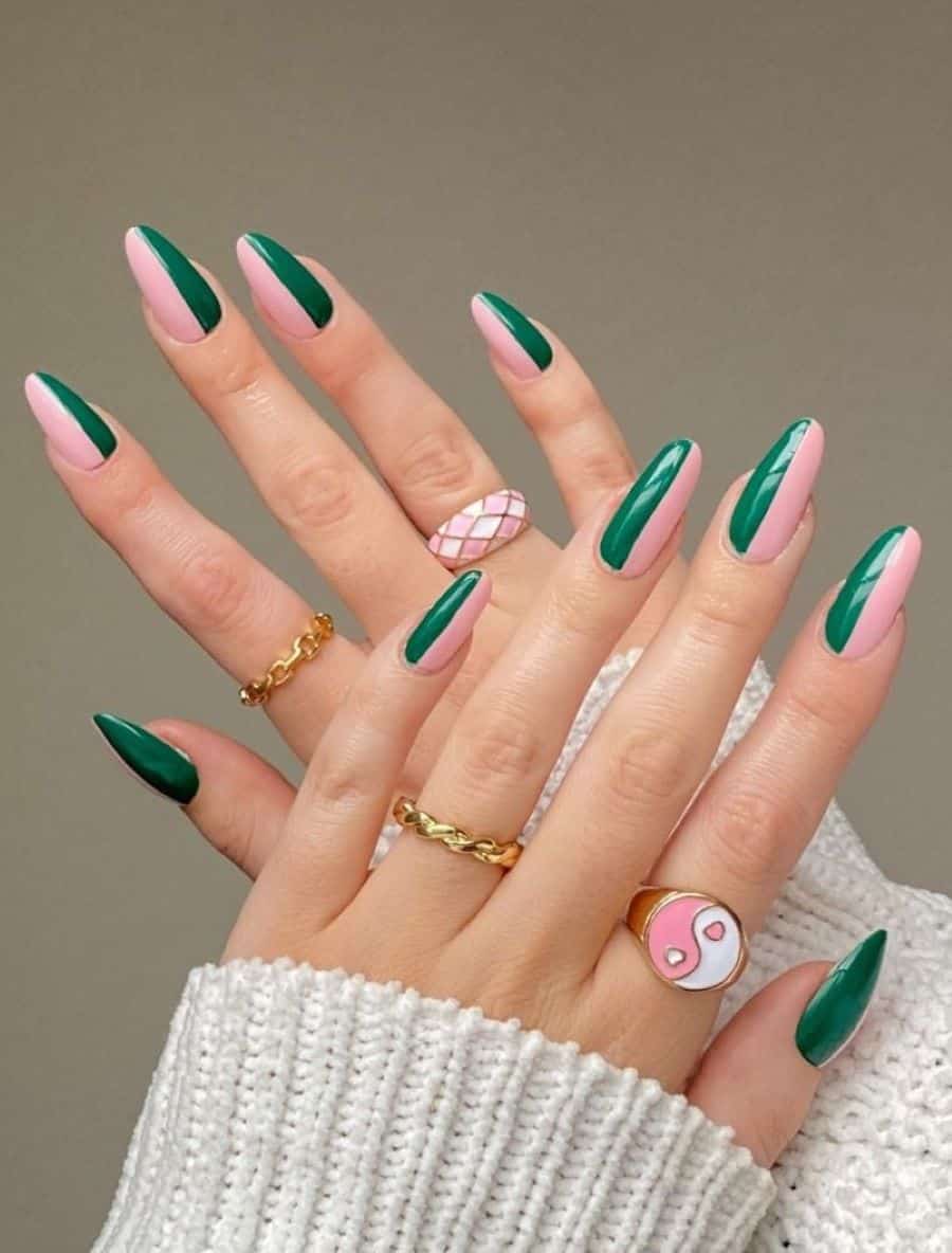 A hand with long almond nails painted half and half with light pink and emerald green