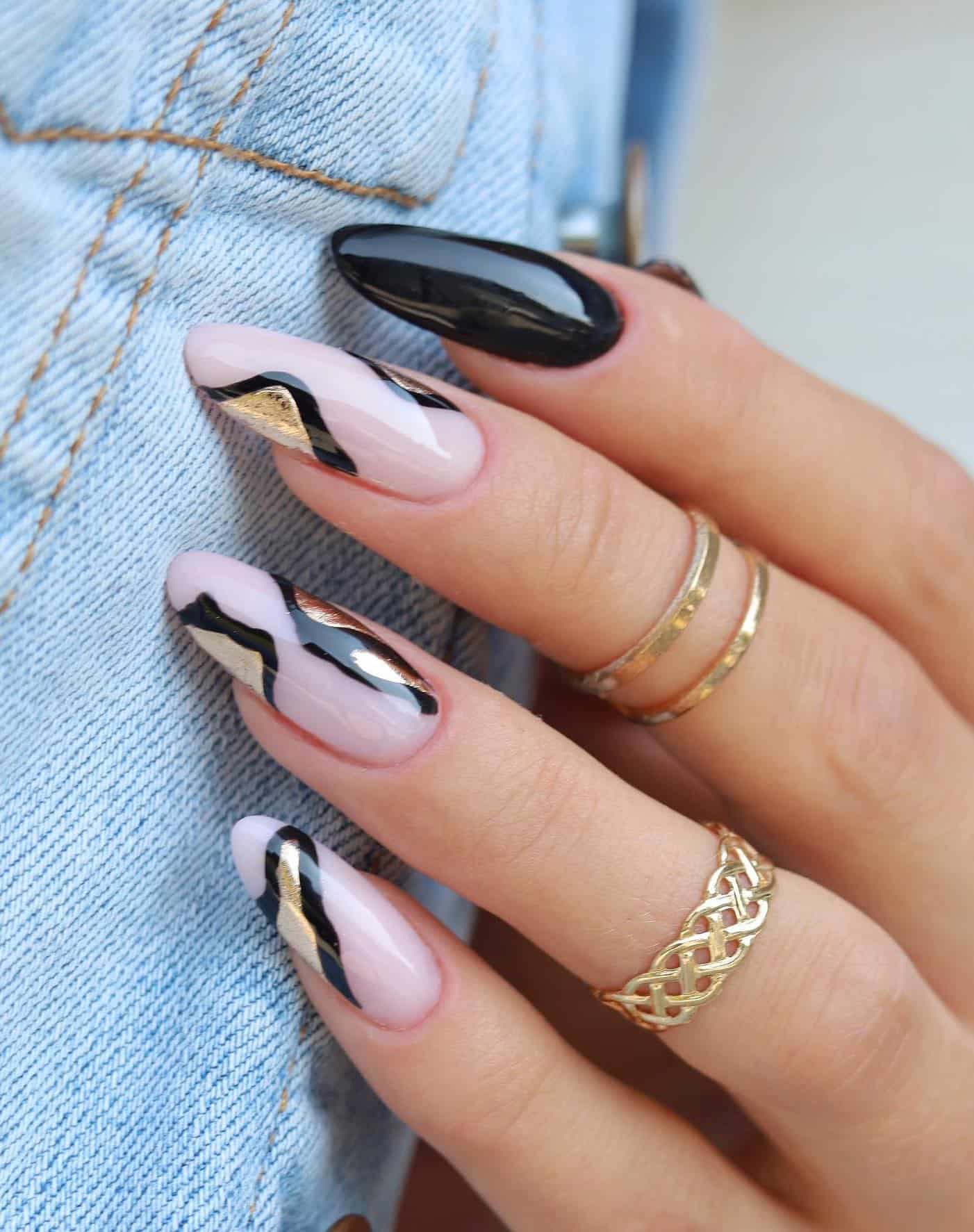Long nude pink almond nails with black and gold details and solid-colored black accent nails