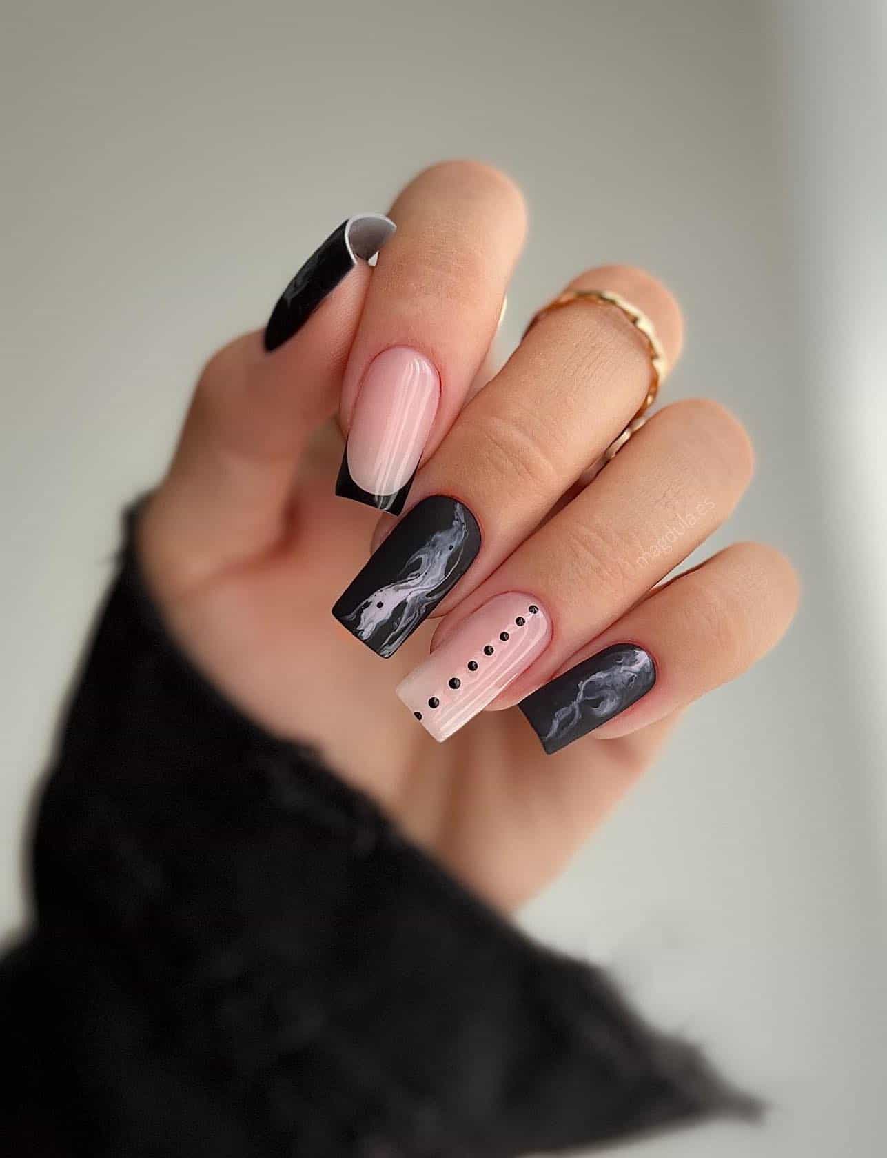 Medium length square nails with matte black marbled nails and nude nails with French tips and dot details