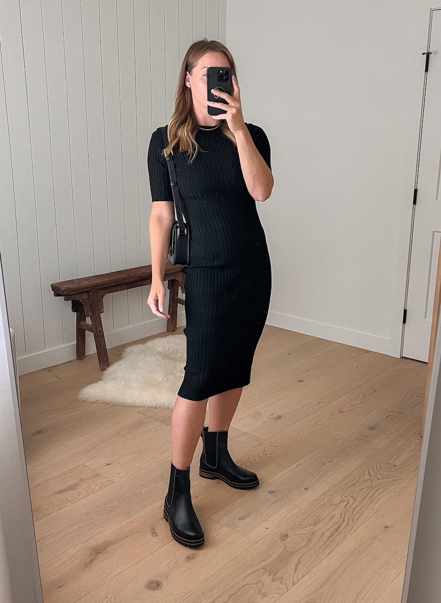 woman wearing a short sleeve midi-length black dress with black Chelsea boots
