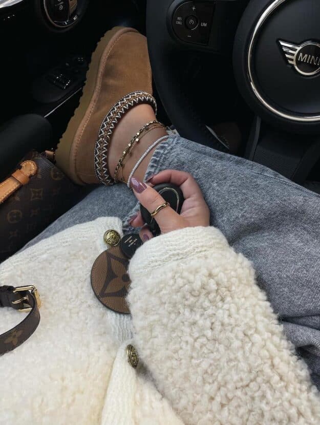 An overhead shot of a woman with brown Ugg Tasman slippers wearing a sherpa coat and jeans