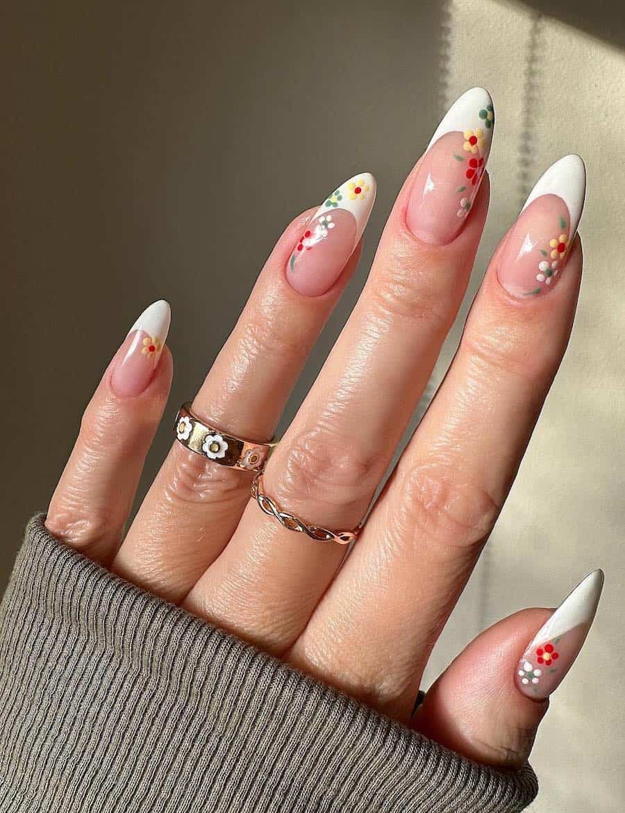 Long almond nails painted in white French tips with floral accents