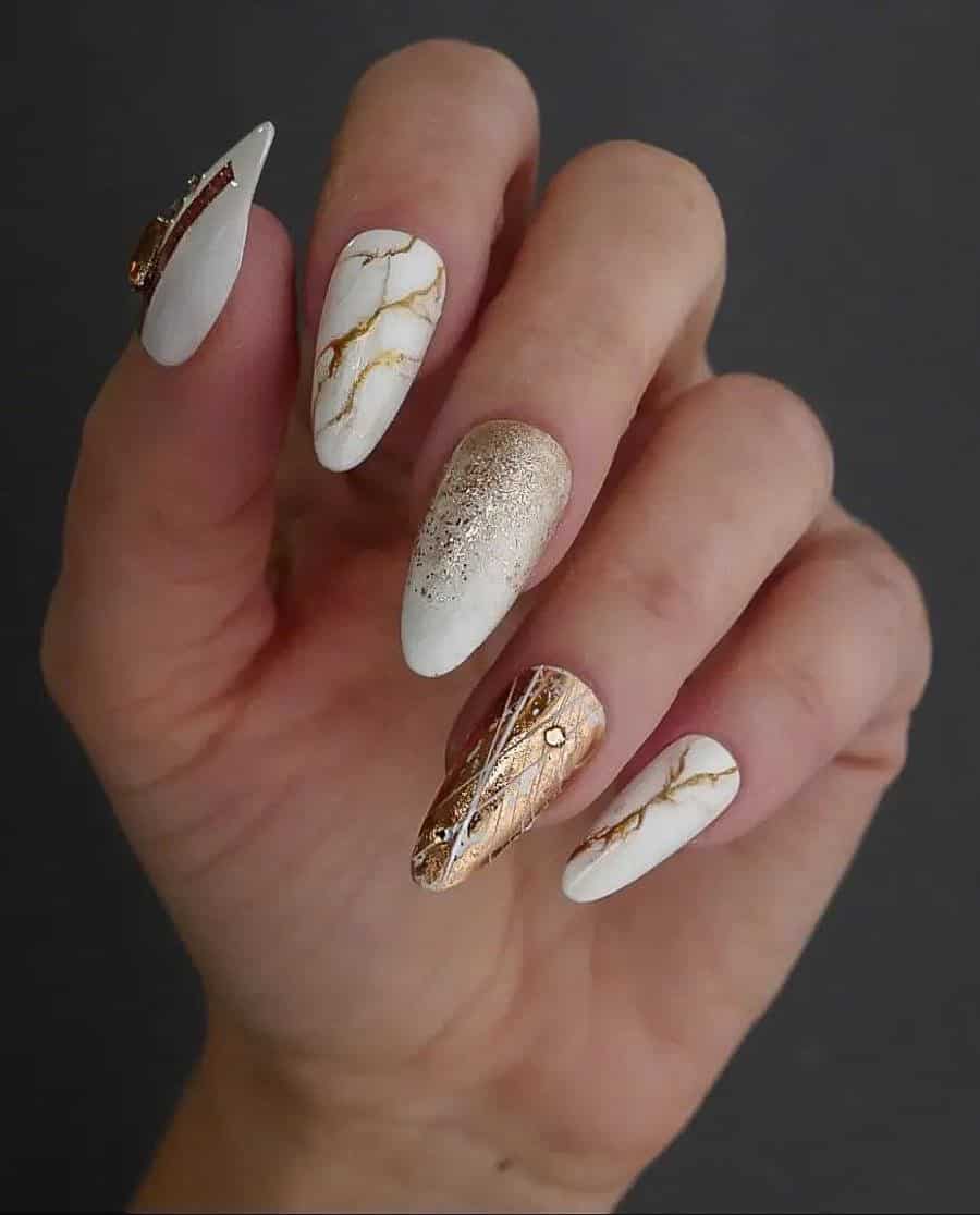 Long white almond nails with gold marbling, gold glitter ombre, and other gold designs