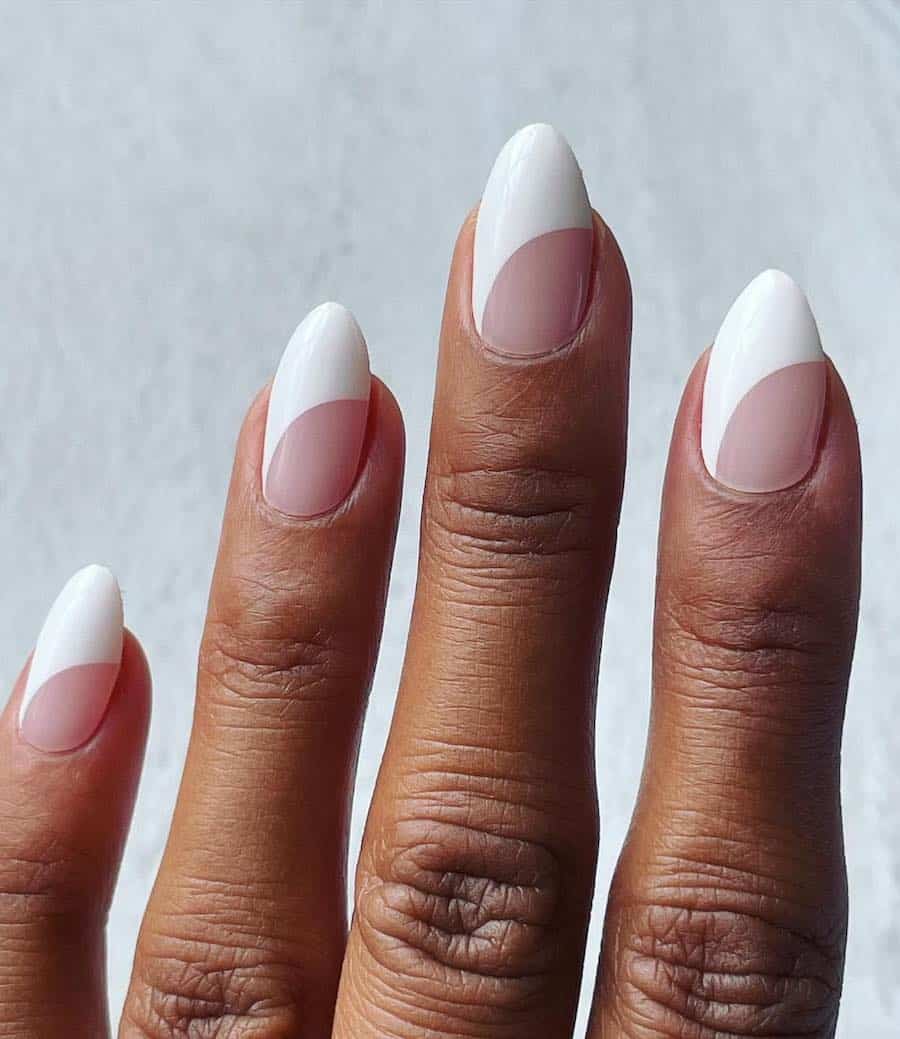 Short almond nails with white polish and curved nude accents