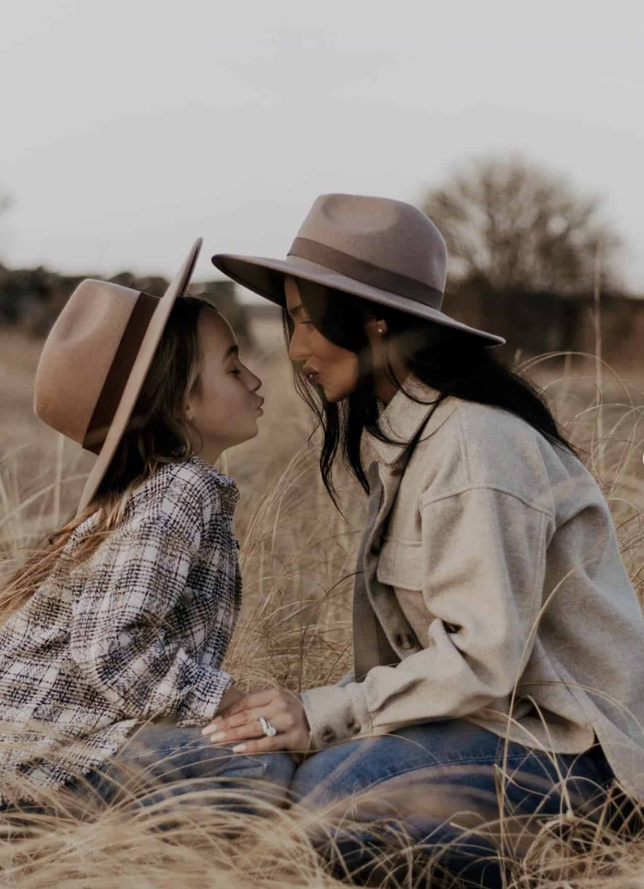 mother and daughter in a field wearing fedora hats and a shirt jacket and plaid shirt