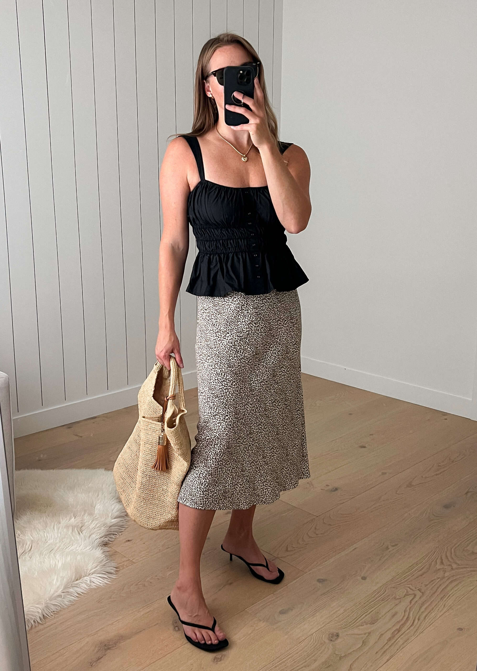 Woman wearing a brown and white speckled midi skirt with a black tank top and black sandals.