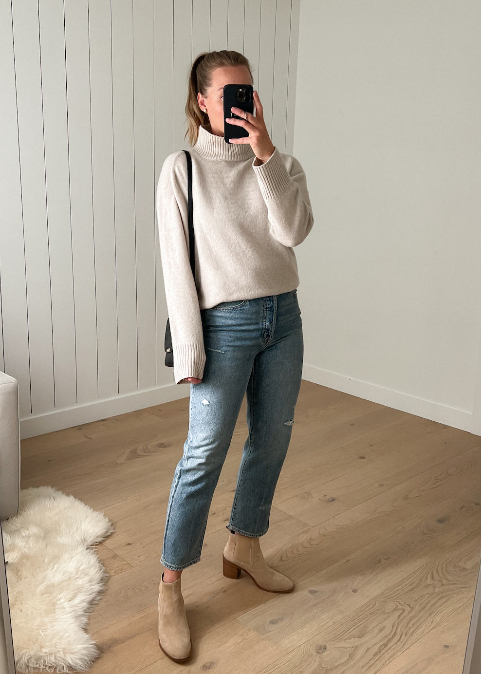 Woman wearing jeans, tan Chelsea boots and a cream turtleneck.