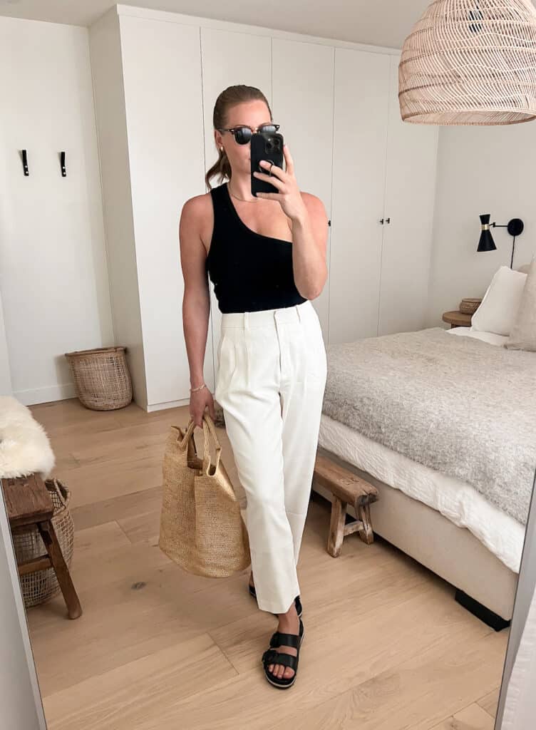 outfit for a Mexico vacation with a black tank top, white linen trousers, and black sandals