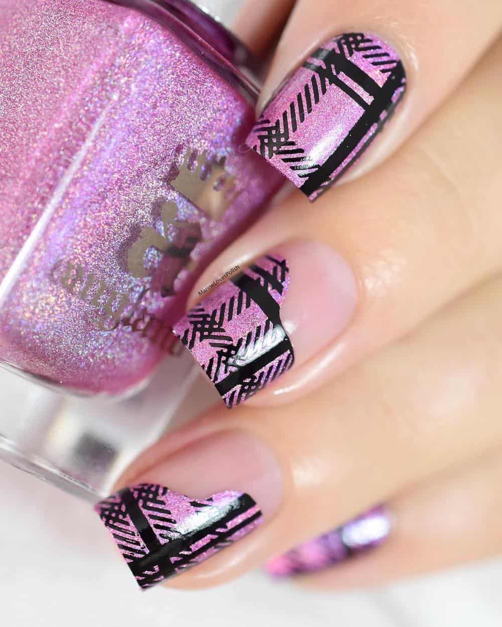 A hand with short square nails painted with pink glitter and black plaid nail art