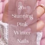 A hand with long almond nails painted with glossy light pink polish and sparkly pink polish, featuring white snowflakes and gingerbread cookie nails art