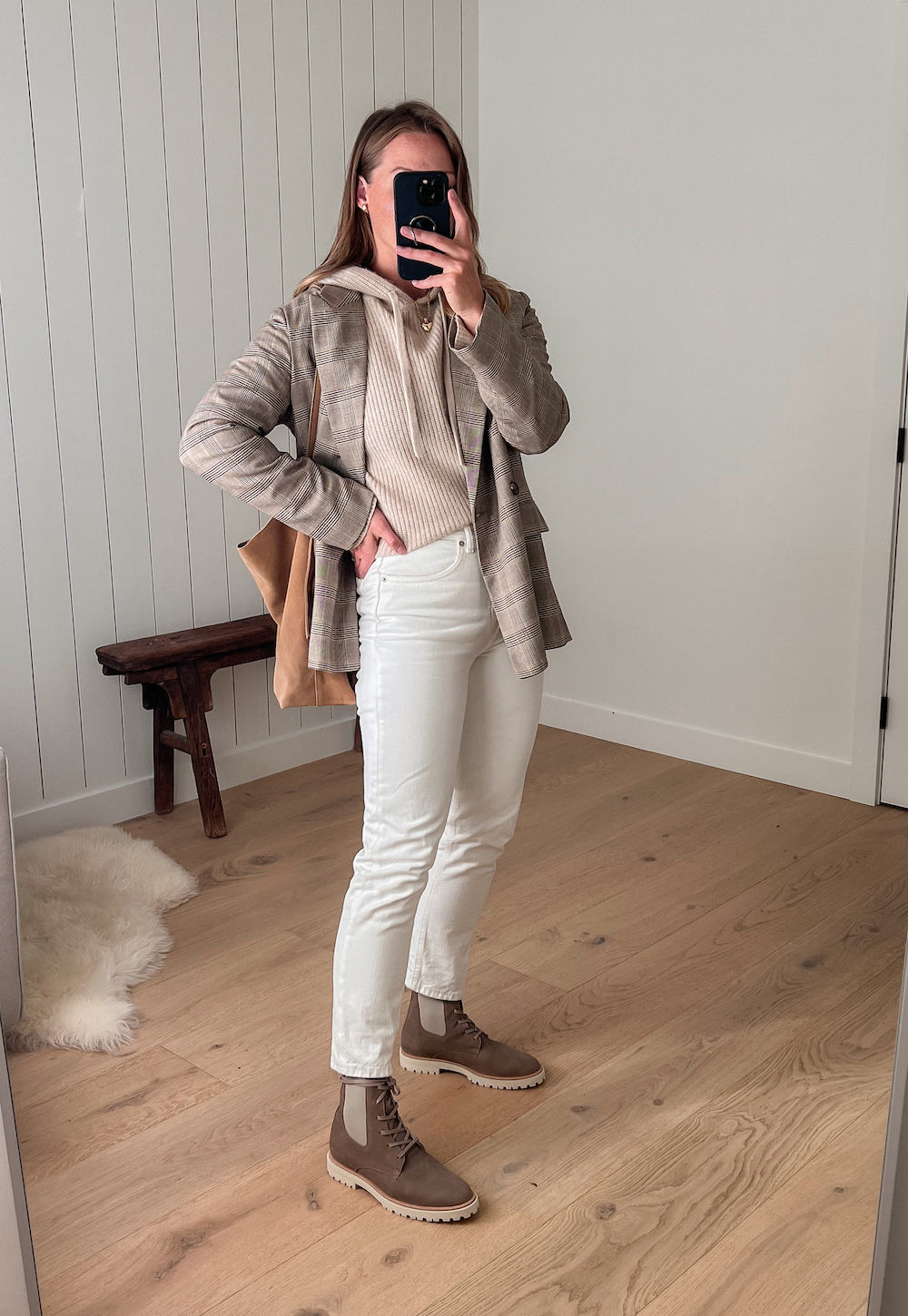 Woman wearing white jeans, brown Chelsea boots, a cream sweater and a tan plaid blazer.